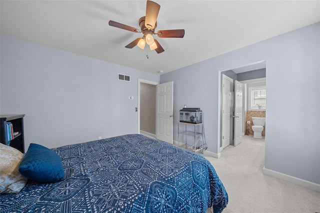 carpeted bedroom featuring visible vents, a ceiling fan, ensuite bathroom, and baseboards