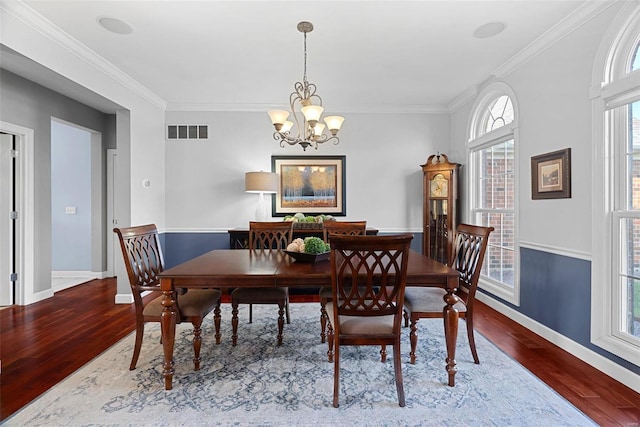 dining area featuring crown molding, wood finished floors, visible vents, and a chandelier