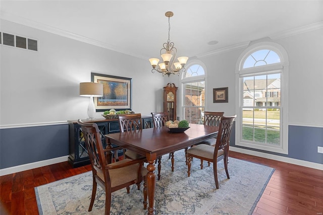 dining space featuring visible vents, a healthy amount of sunlight, crown molding, a notable chandelier, and wood-type flooring