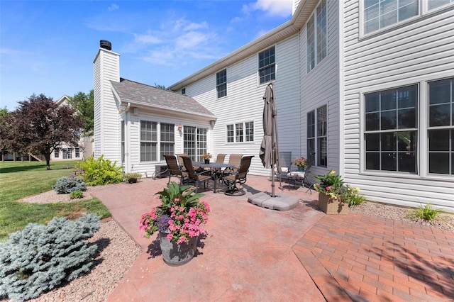 back of property featuring a yard, a patio, and a chimney