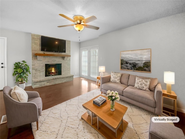 living room with a fireplace, wood finished floors, a ceiling fan, and baseboards