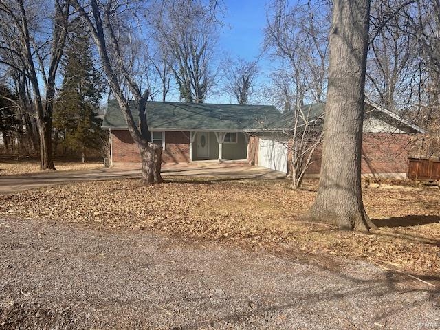 view of front of property featuring brick siding, driveway, and a garage