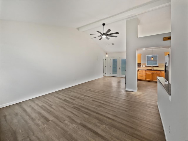 unfurnished living room with ceiling fan, beam ceiling, a sink, and wood finished floors