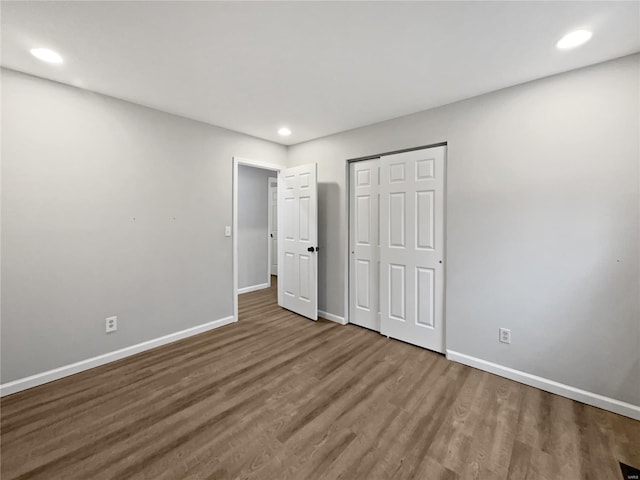 unfurnished bedroom featuring a closet, recessed lighting, wood finished floors, and baseboards