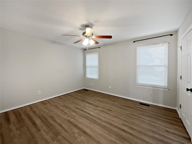 unfurnished room featuring baseboards, visible vents, ceiling fan, and wood finished floors