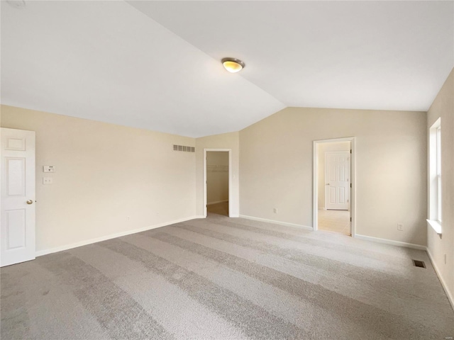 carpeted empty room with lofted ceiling, visible vents, and baseboards