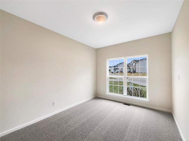 spare room with carpet, visible vents, and baseboards