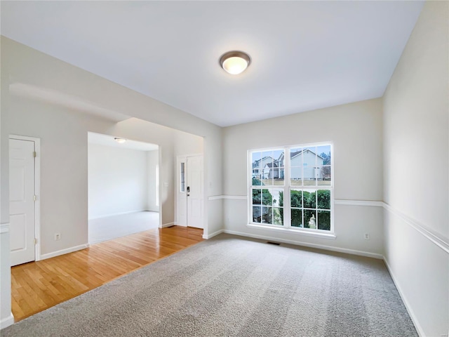 spare room with carpet flooring, visible vents, and baseboards