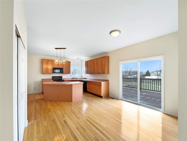 kitchen with decorative light fixtures, light countertops, brown cabinetry, a kitchen island, and black appliances