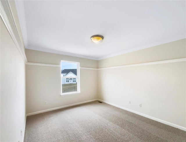 carpeted empty room featuring ornamental molding and baseboards