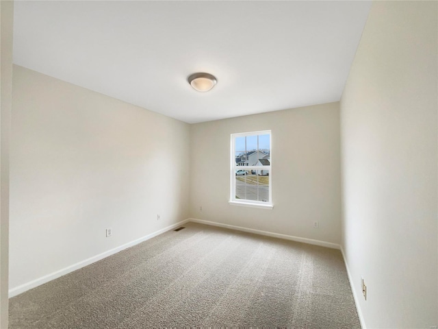 unfurnished room with carpet, visible vents, and baseboards