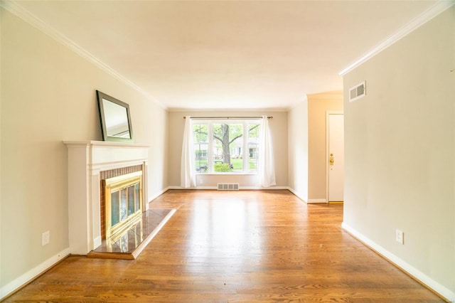 unfurnished living room with light wood-style flooring, visible vents, baseboards, and a glass covered fireplace