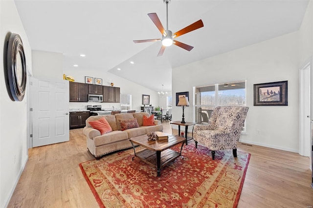 living room featuring vaulted ceiling, light wood-style flooring, ceiling fan with notable chandelier, and baseboards