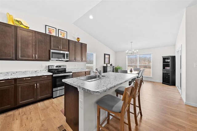 kitchen featuring a breakfast bar, a sink, stainless steel appliances, light countertops, and a chandelier