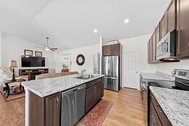 kitchen with light wood finished floors, stainless steel appliances, an island with sink, and a sink