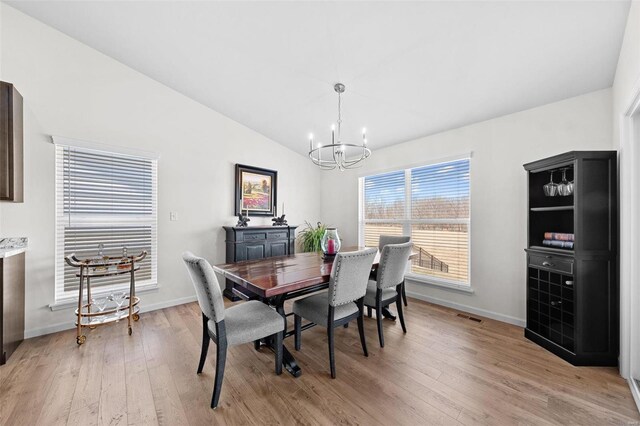 dining room featuring light wood finished floors, visible vents, baseboards, lofted ceiling, and a notable chandelier