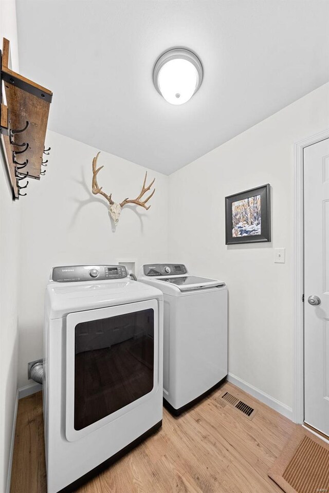 laundry room with visible vents, washing machine and dryer, light wood finished floors, baseboards, and laundry area