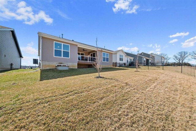 rear view of property with a lawn, ceiling fan, and fence