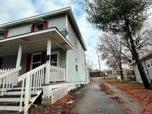 view of side of property featuring a porch and driveway