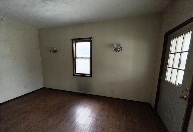 unfurnished room featuring dark wood-style floors and a healthy amount of sunlight