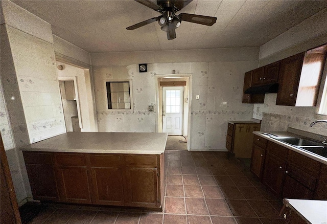 kitchen featuring light countertops, a sink, dark brown cabinets, and ceiling fan