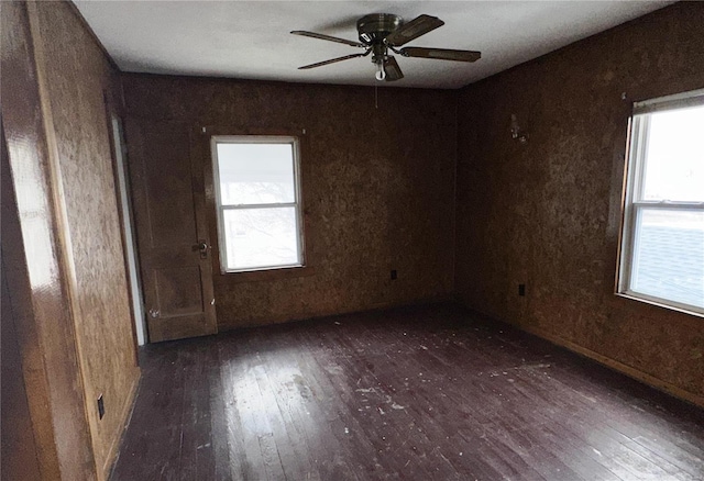 empty room featuring ceiling fan, dark wood-type flooring, and plenty of natural light