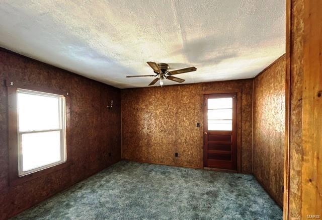 carpeted empty room with ceiling fan and a textured ceiling