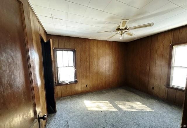 spare room featuring light carpet, wood walls, and ceiling fan