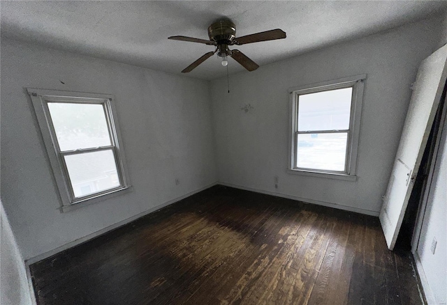 empty room with dark wood-style flooring, ceiling fan, and baseboards