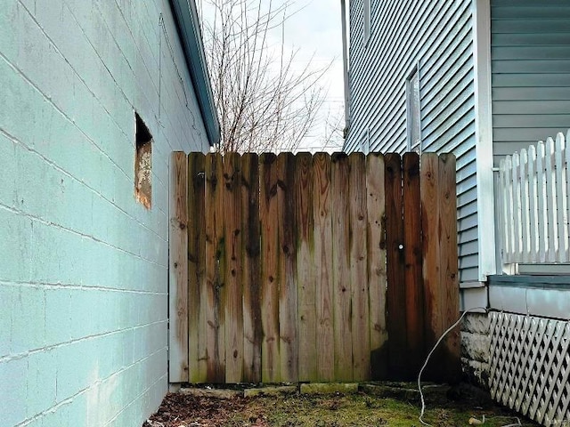 view of side of home featuring fence and concrete block siding