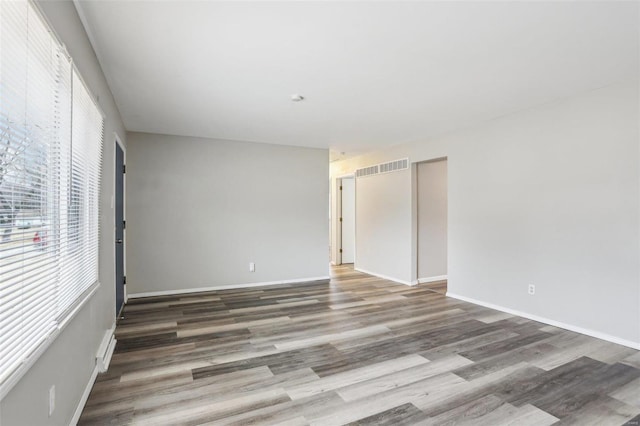 spare room with baseboards, visible vents, and wood finished floors