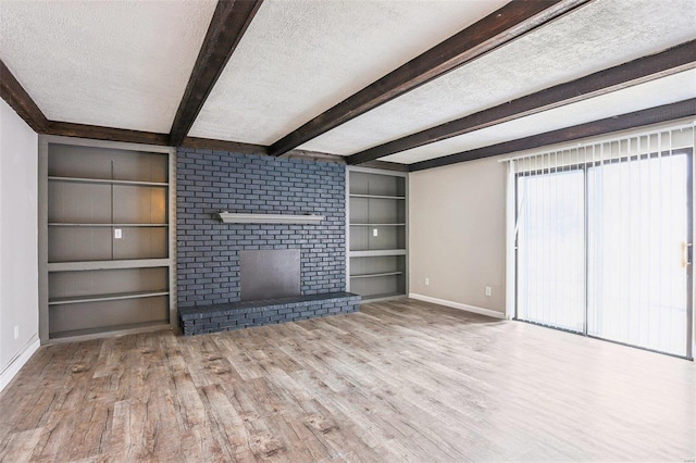 unfurnished living room with built in features, baseboards, beamed ceiling, a textured ceiling, and light wood-type flooring