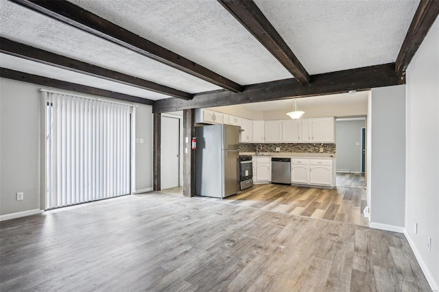 kitchen with light wood finished floors, white cabinets, appliances with stainless steel finishes, a textured ceiling, and a sink