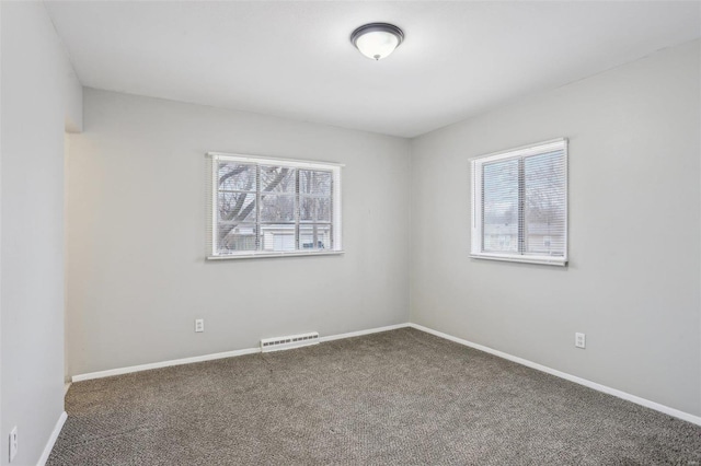 spare room featuring baseboards, visible vents, and dark carpet