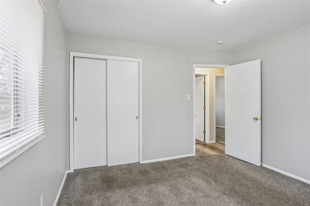 unfurnished bedroom with carpet, a closet, and baseboards