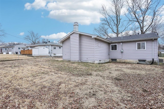 back of house featuring a chimney, fence, and a lawn