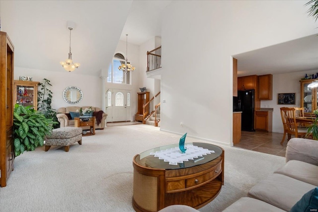 living area featuring light tile patterned floors, light colored carpet, a towering ceiling, a chandelier, and stairs