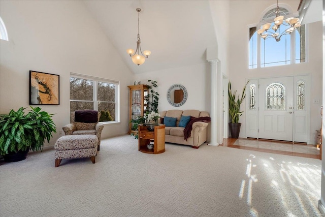 entrance foyer with ornate columns, high vaulted ceiling, carpet, and an inviting chandelier