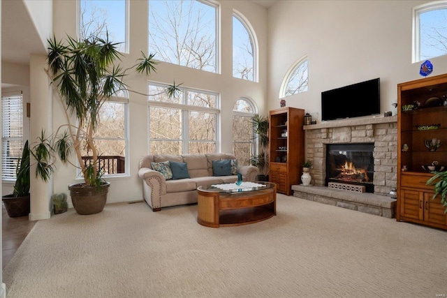 living room featuring a towering ceiling, a fireplace, and carpet flooring