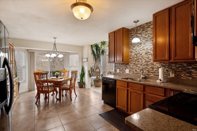 kitchen with brown cabinets, a sink, black appliances, pendant lighting, and backsplash