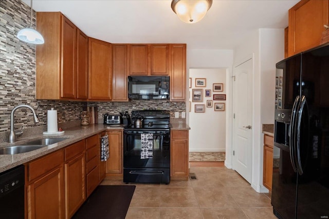 kitchen featuring pendant lighting, brown cabinets, a sink, light stone countertops, and black appliances