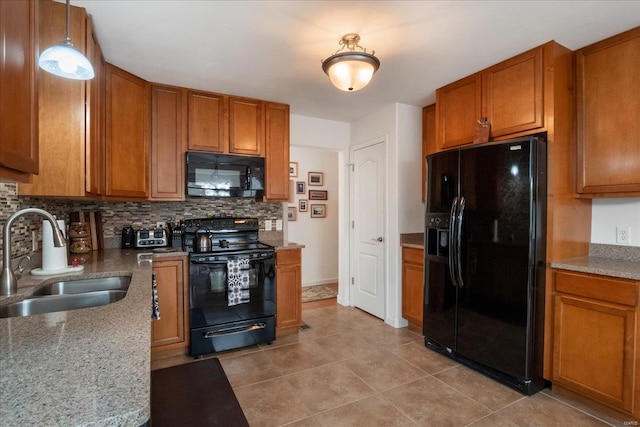 kitchen with pendant lighting, brown cabinets, tasteful backsplash, a sink, and black appliances