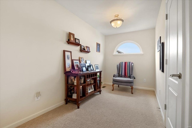 sitting room with baseboards and light colored carpet