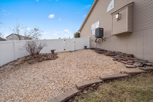 view of yard featuring a gate, fence, and central AC unit