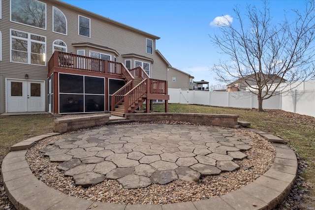 rear view of house with stairway, a sunroom, a patio area, a fenced backyard, and a wooden deck