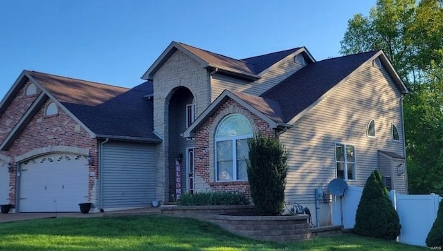 view of front of property with brick siding, concrete driveway, fence, a garage, and stone siding