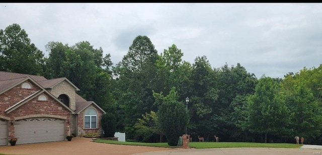 exterior space with driveway, brick siding, a front lawn, and an attached garage