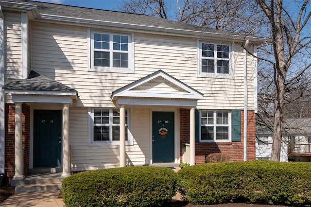 view of front of home featuring roof with shingles and brick siding