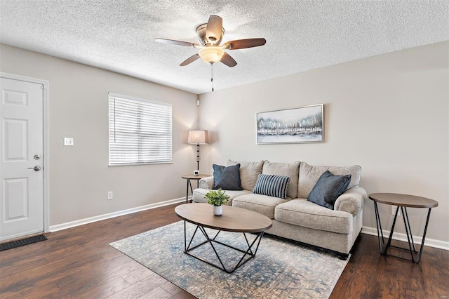 living area featuring dark wood-style floors, a textured ceiling, baseboards, and a ceiling fan