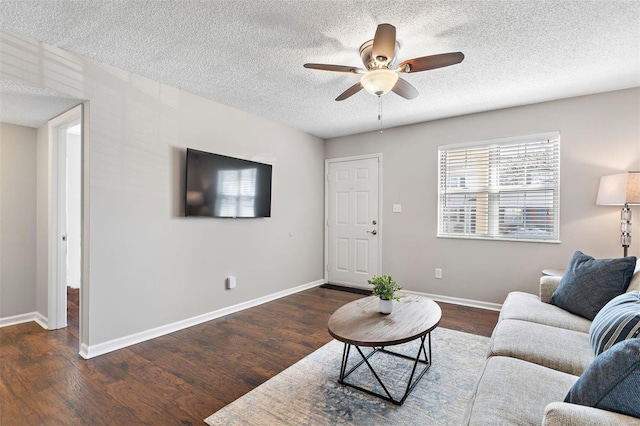 living area with dark wood-style floors, ceiling fan, a textured ceiling, and baseboards